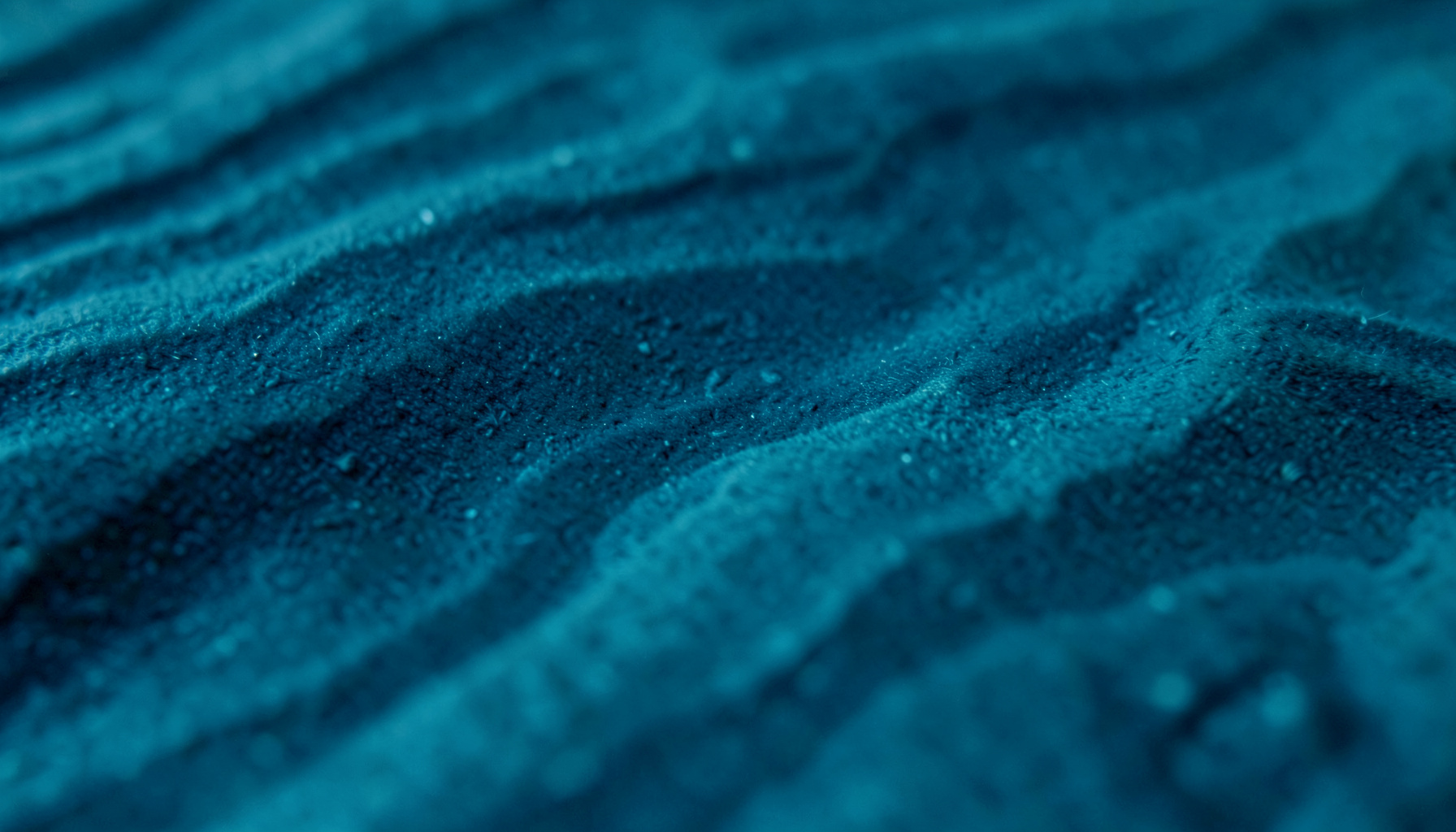 Extreme Nahaufnahme einer strukturierten Oberfläche in tiefem Marineblau mit sanften, organischen Maserungen, die an fließendes Wasser oder Stein erinnert.